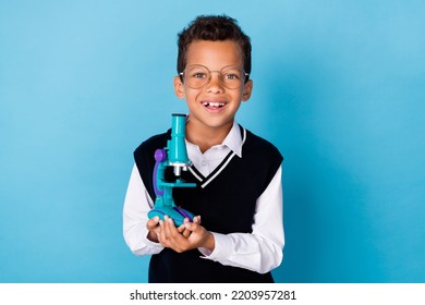 Photo of smart positive boy toothy smile hands hold telescope isolated on blue color background - Powered by Shutterstock