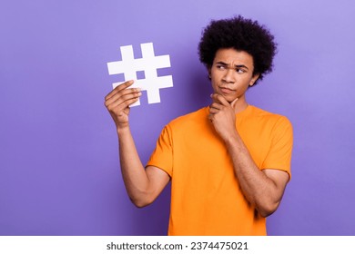 Photo of smart young man touch chin guess how create new tiktok media trend holding hashtag symbol isolated on violet color background