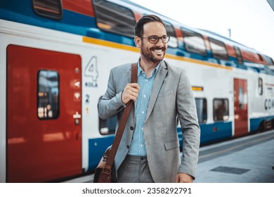 Photo of a smiling businessman at train station.  Confident professional is wearing suit. He is standing at railroad station platform. Businessman at the Train Station - Shutterstock ID 2358292791