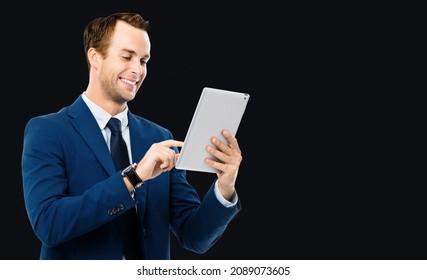 Photo Of Smiling Businessman Using Touchpad Tablet Pc, IPad, Touchpad, Isolated Over Black Background. Business Man In Studio Concept. Copy Space For Some Text.