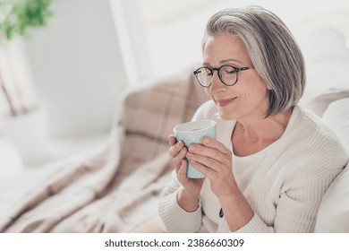 Photo of smiling dreamy elderly lady wear white cardigan enjoying fresh cacao aroma indoors apartment room - Powered by Shutterstock