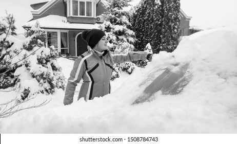 Photo Of Smiling Girl In Green Sport Coat Cleaning A Snow Covered White Car After Blizzard With Brush