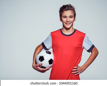 Photo of smiling teen boy in sportswear holding soccer ball - posing at studio
