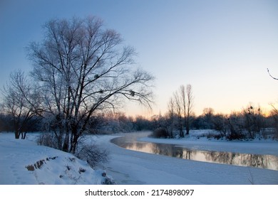 Photo the snow-covered river did not freeze in winter.The river flows in winter. Snow on the branches of trees. Reflection of snow in the river. Huge snowdrifts lie on the Bank of the stream. - Powered by Shutterstock