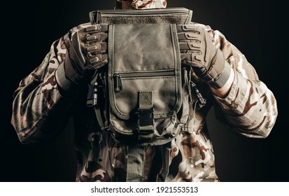 Photo of soldier in camouflaged uniform and tactical gloves holding leg bag on black background close-up view. - Shutterstock ID 1921553513