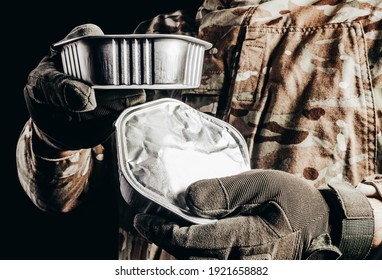 Photo of soldier in camouflaged uniform and tactical gloves holding canned food field ration on black background. - Shutterstock ID 1921658882