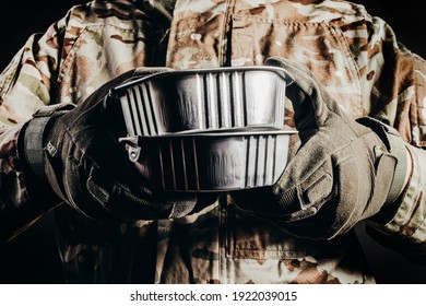 Photo of soldier in camouflaged uniform and tactical gloves holding canned food MRE on black background, close-up view. - Shutterstock ID 1922039015