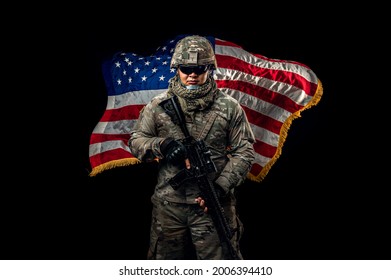 Photo Of Soldier Holding The USA Flag In Background. Special Force United States Soldier Or Military Contractors Holding Rifle. Image On Background. Soldier, Army, War, Weapon And Technology Concept.