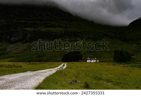Photo of a solitary House Amid Scottish Wilderness, Towering Mountain Backdrop on Cloudy Summer Day, Tranquil Seclusion in Rural Landscape