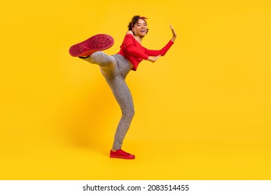 Photo Of Sporty Energetic Lady Leg Hit Camera Show Sole Wear Pin-up Outfit Shiny Pants Isolated Yellow Color Background