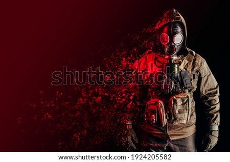 Photo of a stalker soldier in soviet gas mask, jacket and armored vest standing and dissolving with red highlights on one side.