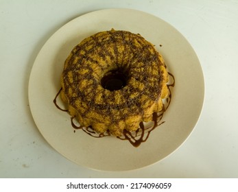 Photo of steamed sponge cake on a white plate and table with chocolate milk topping. - Shutterstock ID 2174096059