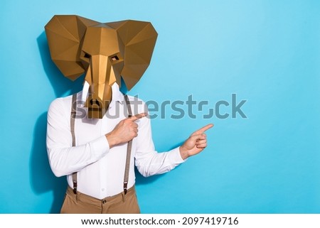 Photo of strange eccentric guy dressed wild animal mask pointing empty space isolated blue color background