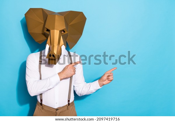 Photo of strange\
eccentric guy dressed wild animal mask pointing empty space\
isolated blue color\
background