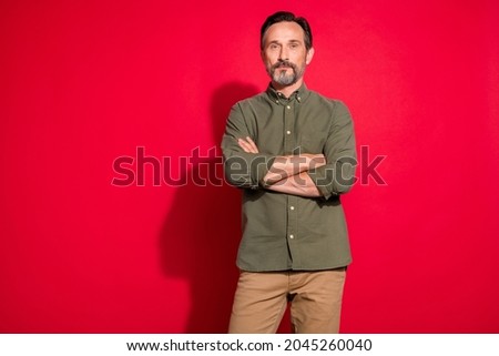 Photo of strict mature brunet man crossed arms wear green shirt isolated on red color background