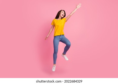 Photo of strong funky young lady wear yellow t-shirt jumping high catching isolated pink color background