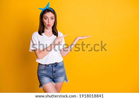 Photo of stylish brown haired point show empty space wear white t-shirt blue pin-up isolated on yellow color background