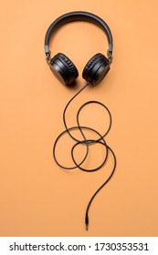 Photo of stylish modern black headphones over beige background.