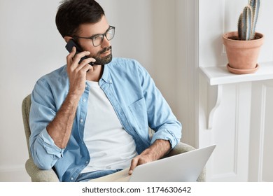 Photo Of Successful Entrepreneur Conducts Negotiations With Investors Via Modern Gadgets, Involved In Electronic Bussiness, Manages Project Freelance Or Distantly, Has Telephone Conversation