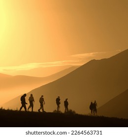 Photo of a sunrise with mountains and people hiking - Shutterstock ID 2264563731