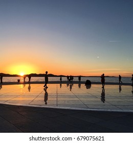 Photo Of Sunset Taken In Zadar, Croatia. People Enjoying Sun Salutation And Listening To Sea Organ.