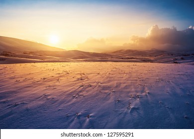 Photo of a sunset at winter snowy mountains, peaceful stunning landscape, amazing seasonal nature, cold weather in the park, beautiful sunny snow field, wintertime scene, icy lands - Powered by Shutterstock