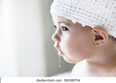 Photo Of A Surprised Baby Girl Drooling With A White Knitted Hat