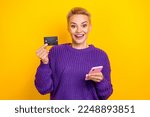 Photo of surprised blonde short hair wear violet knit jumper hold phone ecard sale for visa mastercard owner isolated on yellow color background