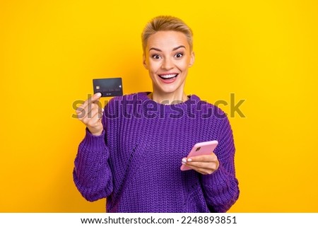Photo of surprised blonde short hair wear violet knit jumper hold phone ecard sale for visa mastercard owner isolated on yellow color background