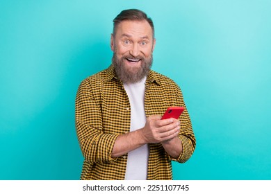 Photo of surprised funky man wear trendy yellow shirt hold his new phone use special app telegram chatting isolated on aquamarine color background - Powered by Shutterstock