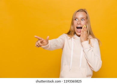 Photo Of Surprised School Girl With Dental Braces Pointing Finger Aside At Copyspace Isolated Over Yellow Background