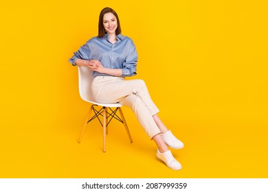 Photo of sweet adorable young lady dressed blue outfit sitting chair smiling isolated yellow color background