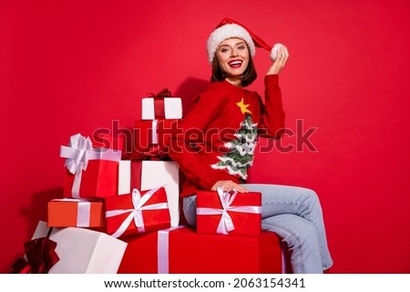 Photo of sweet charming young lady dressed print pullover smiling sitting christmas presents isolated red color background