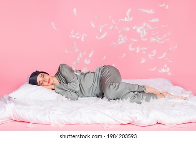 Photo Of Sweet Charming Young Woman Nightwear Lying Duvet Sleeping Feather Flying Isolated Pastel Pink Color Background