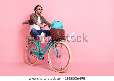 Photo of sweet cute guy dressed brown shirt dark eyeglasses riding bike backpack looking empty space isolated pink color background