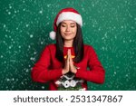 Photo of sweet dreamy girl dressed ugly print red x-mas pullover headwear closed eyes making wishes isolated green color background