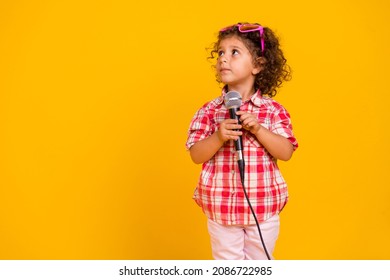 Photo Of Sweet Dreamy Schoolgirl Wear Plaid Outfit Heart Glasses Looking Empty Space Holding Mic Isolated Yellow Color Background