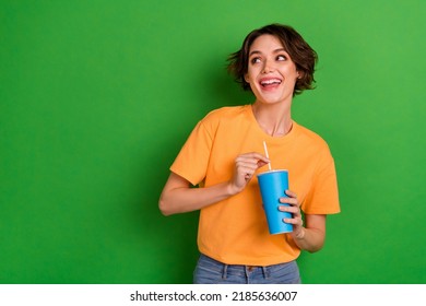 Photo Of Sweet Dreamy Young Lady Wear Orange Outfit Drinking Soda Looking Empty Space Isolated Green Color Background