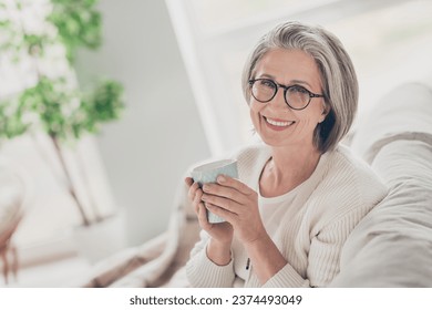 Photo of sweet good mood senior lady dressed white cardigan eyewear drinking tea indoors house room - Powered by Shutterstock