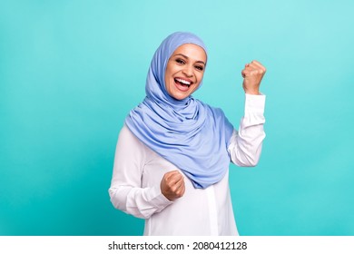 Photo Of Sweet Lucky Young Woman Wear Arab Headscarf Rising Fists Smiling Isolated Turquoise Color Background