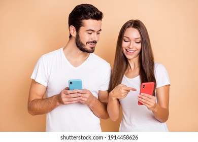 Photo of sweet married couple dressed white t-shirts looking pointing modern device isolated beige color background