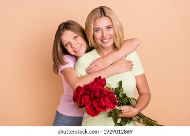 Photo of sweet pretty mother daughter wear casual outfit hugging holding flowers bouquet isolated beige color background