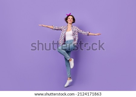 Photo of sweet pretty woman wear plaid shirt jumping high arms sides isolated violet color background