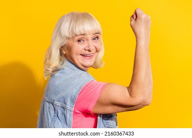 Photo Of Sweet Strong Lady Pensioner Dressed Denim Waistcoat Showing Arm Biceps Isolated Yellow Color Background