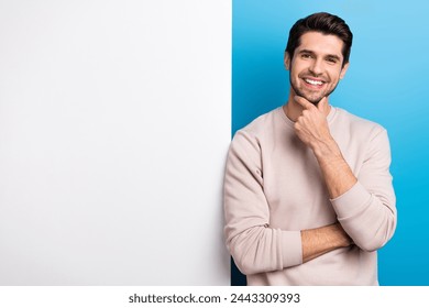 Photo of sweet thoughtful man wear beige sweatshirt arm chin poster empty space isolated blue color background - Powered by Shutterstock