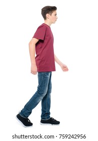 Photo Of Teen Boy Walking At Studio Over White Background. Profile Portrait