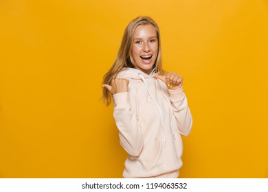 Photo Of Teen School Girl With Dental Braces Pointing Finger Backward At Copyspace Isolated Over Yellow Background
