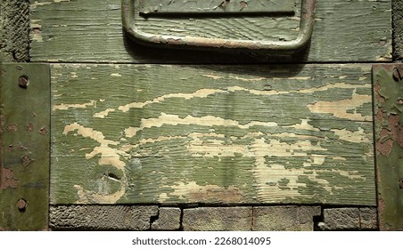 Photo of the texture of a military wooden box from under a weapon.Wooden green background in military style.A green box with a metal handle.