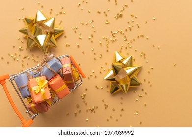 In The Photo There Are Candies In A Vase. Also, Golden Confetti Is Scattered On A Light Beige Background. Decor. Beautiful Festive Still Life. Bright Lighting. There Are No People In The Photo.