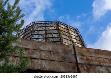 Photo of a thermoelectric plant with big chimneys at the background of blue sky. Fence and green trees.